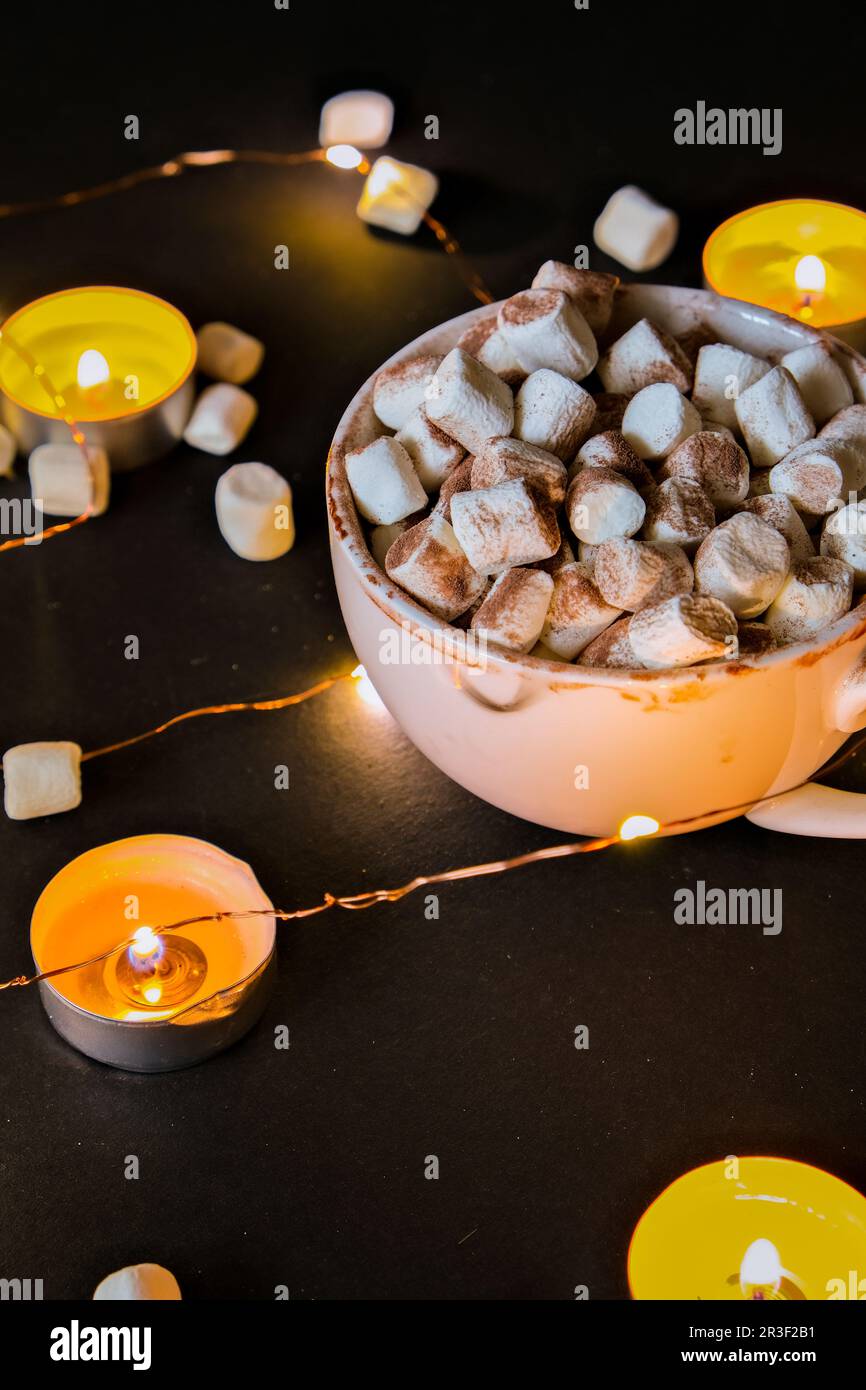 Tasse mit heißem Winter Kakao und Marshmallows in der Nacht. Weihnachtsbeleuchtung. Teelicht Kerzen. Gute Nacht süße Träume. Stockfoto