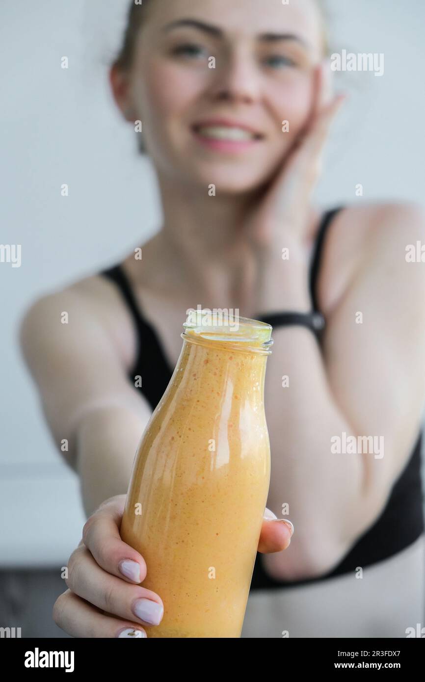 Junge, blonde Frau, die vegane Smoothies trinkt, trinkt Entgiftung. Frau, die zu Hause Yoga macht. Saubere Ernährung, Gewichtsverlust, Stockfoto