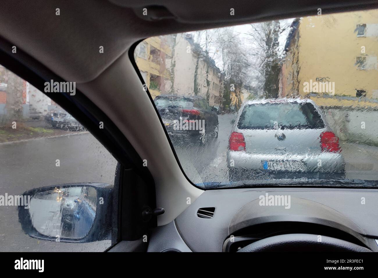 Blick aus dem Auto durch eine regendurchflutete Scheibe mit einer unklaren Sicht auf den Verkehr, Witten, Deutschland Stockfoto