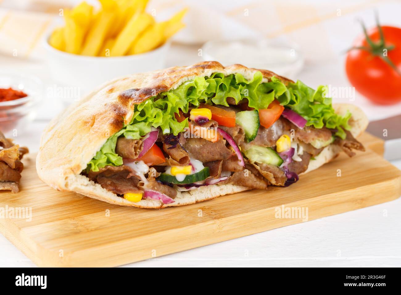 Döner Kebab Döner Kebab Half Food in Pita-Brot mit Pommes auf Holzbrett ...