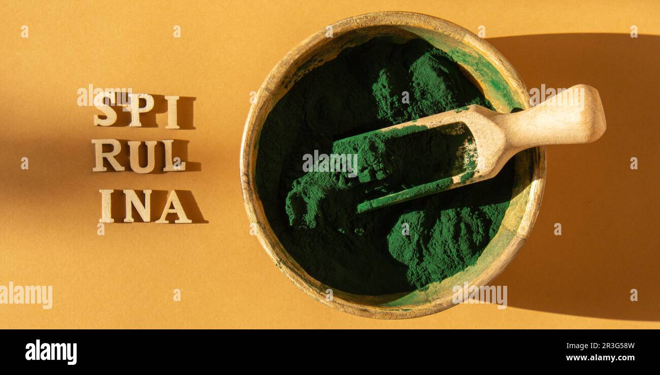 Blau-grüne Algen-Spirulina-Pulver in Bambus-Eco-Schüssel mit dem Text SPIRULINA. Superpulver im Löffel. Nahrungsergänzungsquelle von Prote Stockfoto
