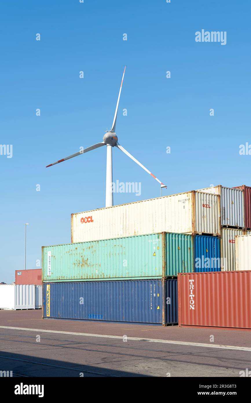 Container aus der ganzen Welt im Hafen von Magdeburg. Im Hintergrund eine Windturbine. Stockfoto