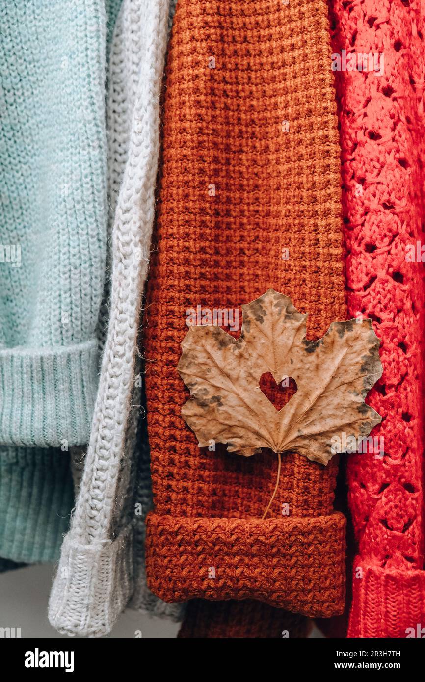 Herbstkonzept. Herzzaugliches Ahornblatt auf kuschelig warmem Pullover. Strickpullover aus Wolle und Mohair. Hygge-Stil Stockfoto