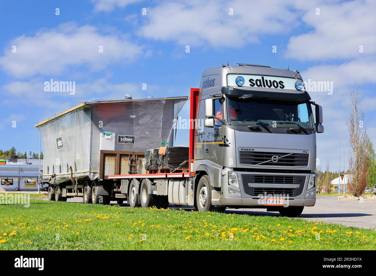 Silberner Volvo FH-Lkw, der an einem sonnigen Tag eine Salvos-Blockkabine als außergewöhnliche Ladung transportiert und auf dem Rastplatz geparkt hat. Forssa, Finnland. 19. Mai 2023. Stockfoto