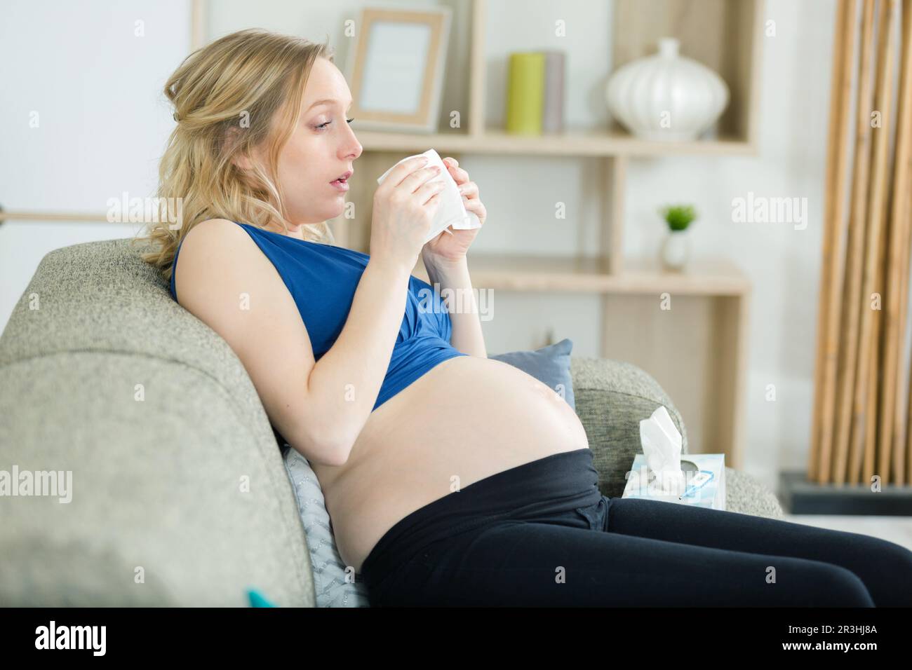 Schwangere Frau auf dem Sofa, die erkältet ist Stockfoto
