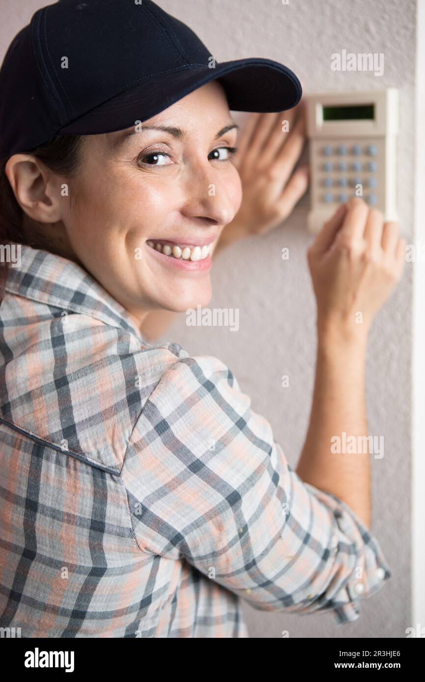 Bild einer Frau, die lächelt, während sie den Türcode drückt Stockfoto