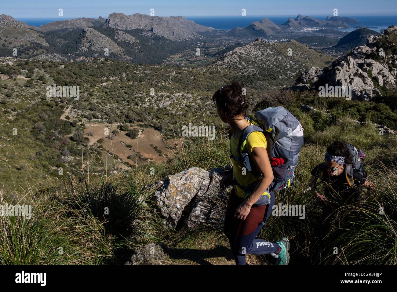 Wanderer steigen auf Cucuia de Fartaritx mit Alcudia Bucht im Hintergrund, Pollença, Mallorca, Balearen, Spanien. Stockfoto