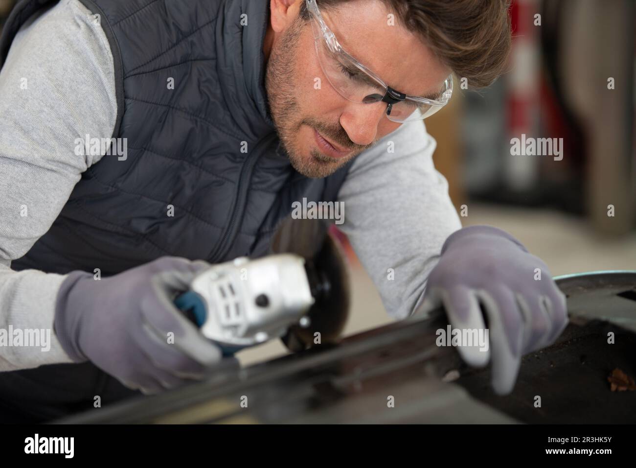 Mann mit Winkelschleifer auf Karosserie Stockfoto