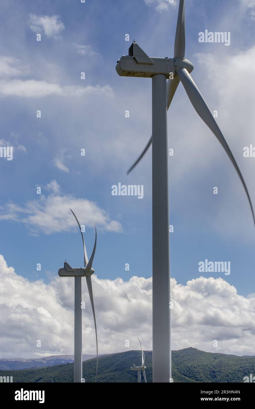 Windmühlen in den Bergen. Bergkette mit grünem Gras, weiße flauschige Wolken am blauen Himmel. Stockfoto