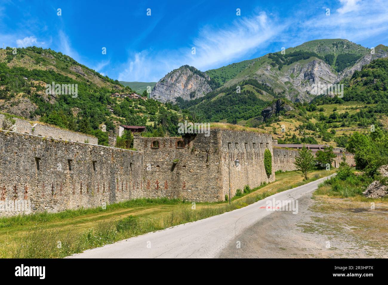 Blick auf die schmale Straße entlang der alten militärisch-alpinen Festung als Berge unter blauem Himmel im Hintergrund in Vinadio, Italien. Stockfoto