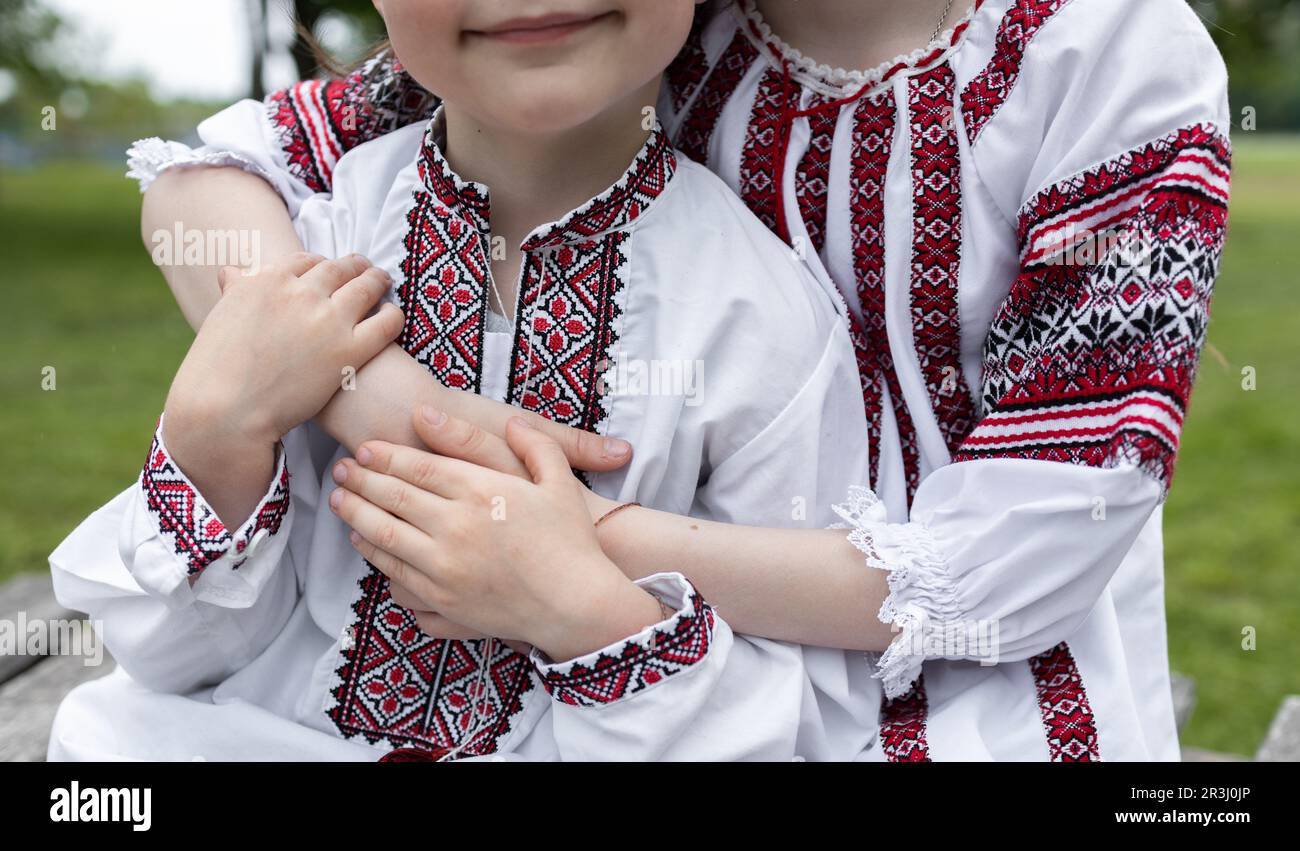 Die Hände zweier Kinder, die in traditionell gestickter ukrainischer Kleidung gekleidet sind, halten sich gegenseitig Stockfoto