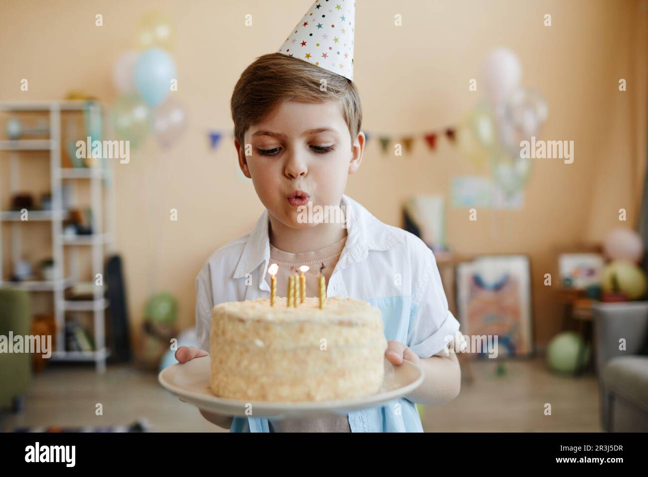 Porträt eines süßen Jungen mit Geburtstagskuchen und Kerzen blasen Stockfoto
