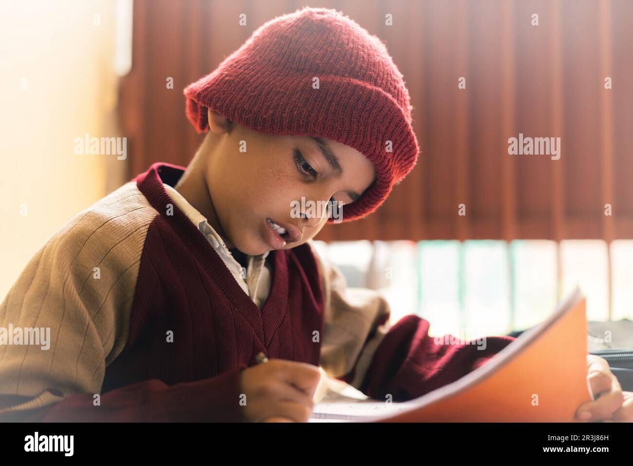Ein indischer Junge, der im Klassenzimmer lernt, auf einem Notizblock schreibt und seine Schuluniform trägt, Bildung und wieder-zur-Schule-Konzept. Stockfoto