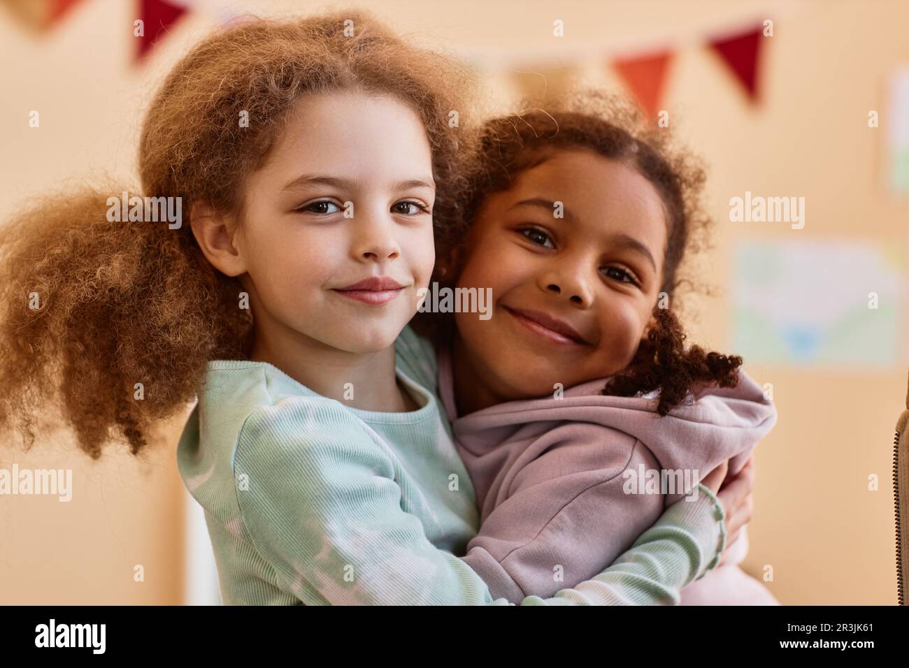 Porträt von zwei süßen kleinen Mädchen, die zu Hause umarmt und vor der Kamera lächelt Stockfoto