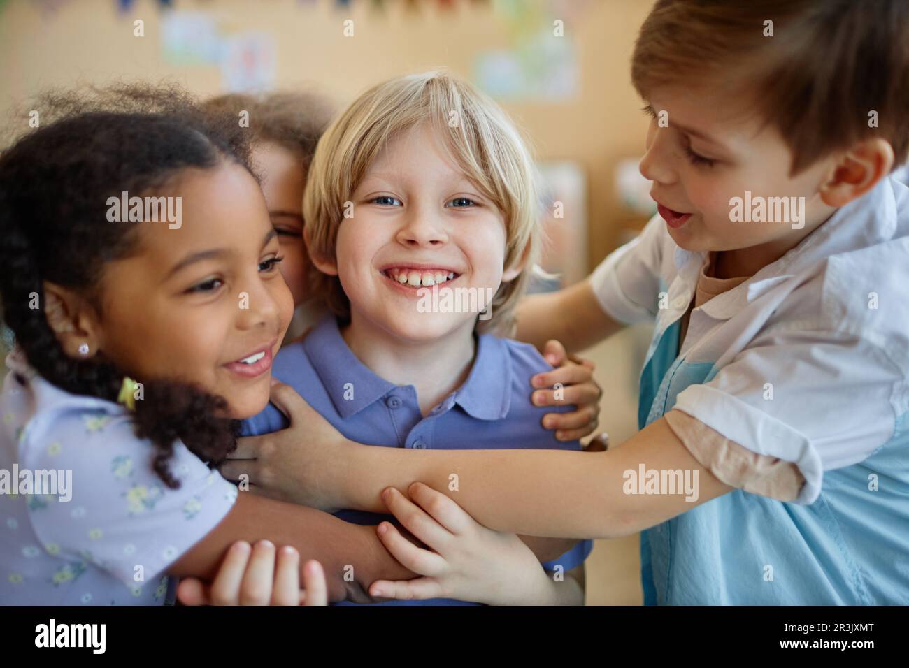 Eine vielfältige Gruppe von Kindern, die sich glücklich umarmen, während sie zusammen spielen und lächeln Stockfoto