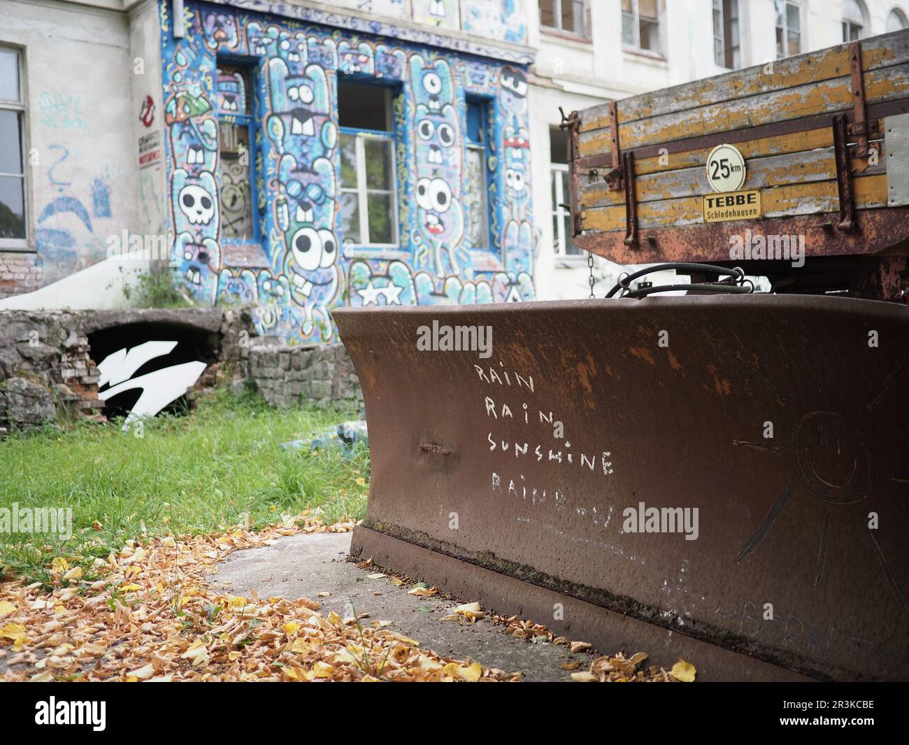 Graber mit Anhängern vor einem verlassenen Gebäude mit Graffiti Stockfoto