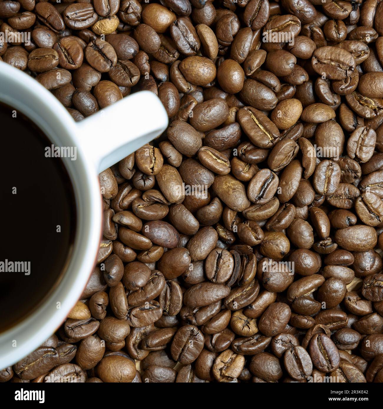 Geröstete Kaffeebohnen und eine Tasse Kaffee auf einem Tisch Stockfoto