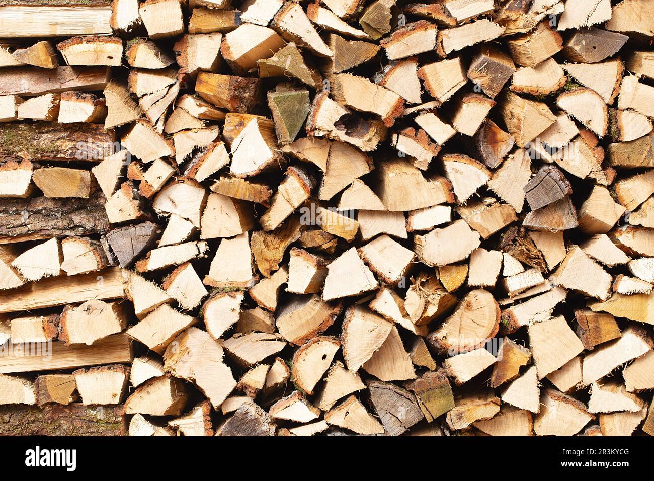 Wand aus Brennholz, Hintergrund aus trocken gehacktem Brennholz. Holzhintergrund. Natürliche Textur. Weltweite Energiekrise. Heizung mit Holz Stockfoto