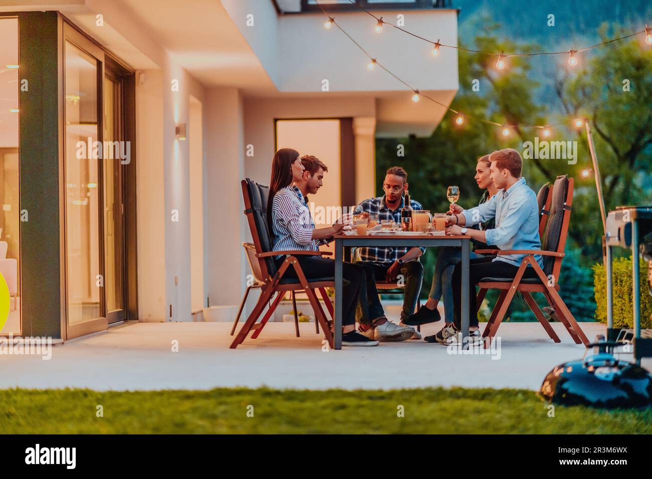 Eine Gruppe junger, vielfältiger Leute, die abends auf der Terrasse