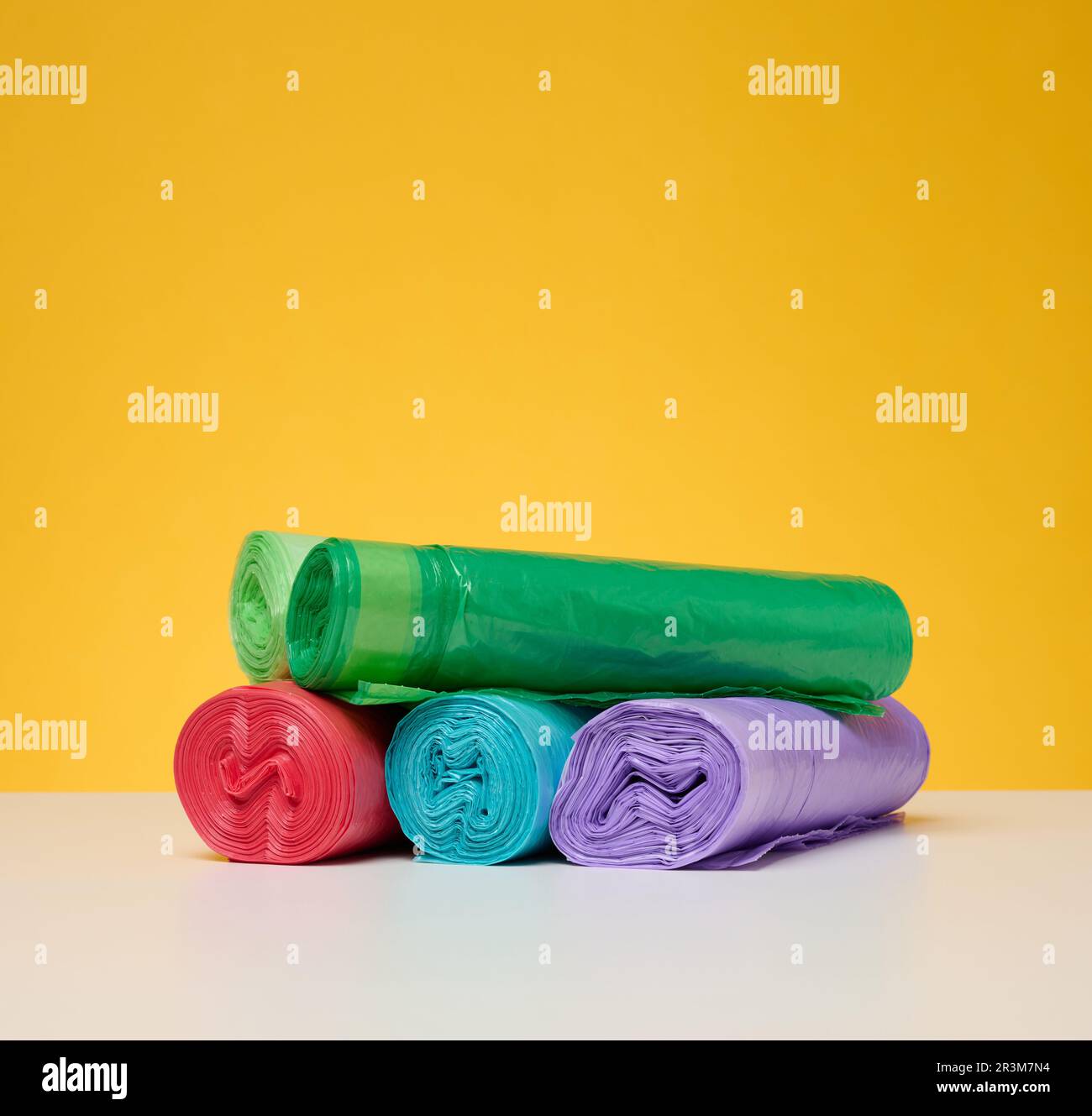 Stapel Einweg-Müllbeutel aus Kunststoff auf gelbem Hintergrund Stockfoto