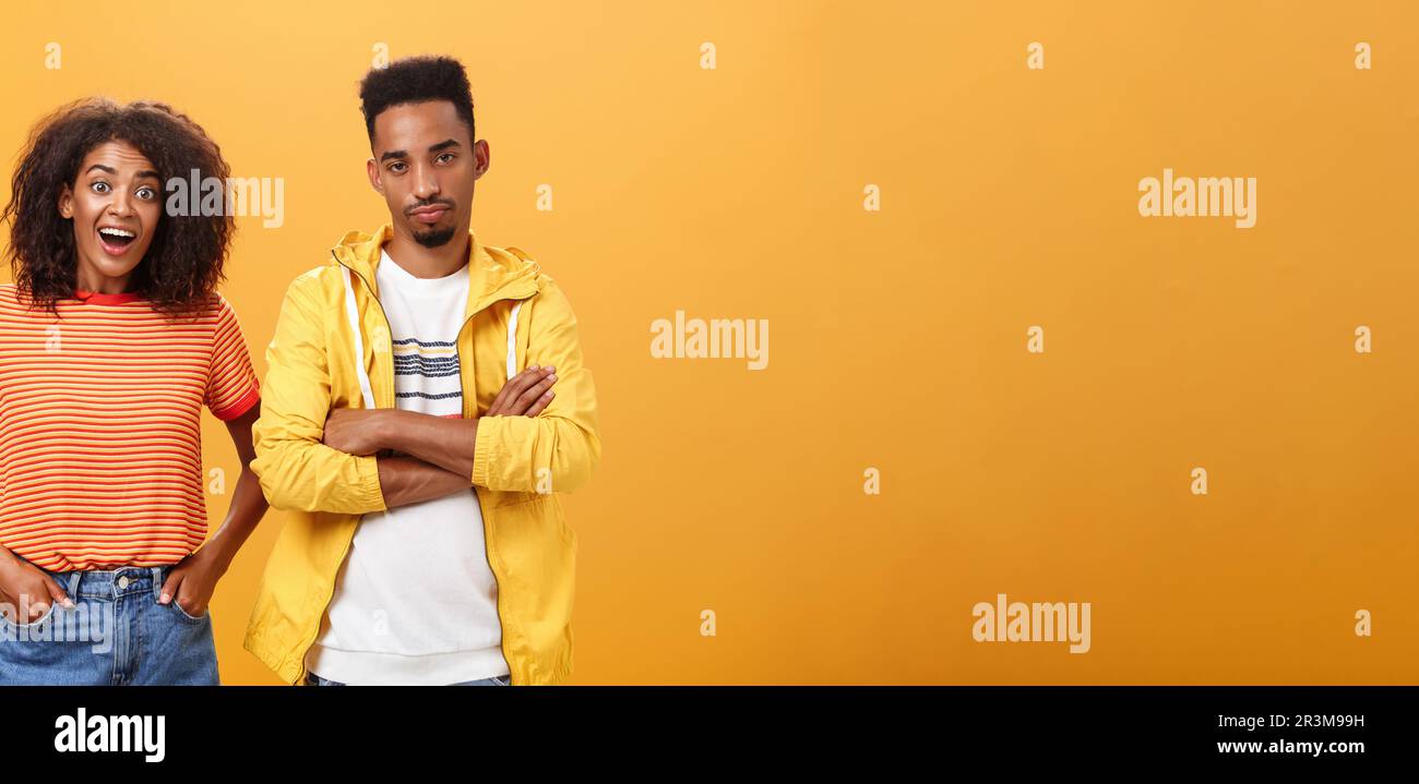 Zwei afroamerikanische Freunde stehen über orangefarbenem Hintergrund, Mädchen denkt Idee ist genial Gefühl aufgeregt und fröhlich, während boyfr Stockfoto
