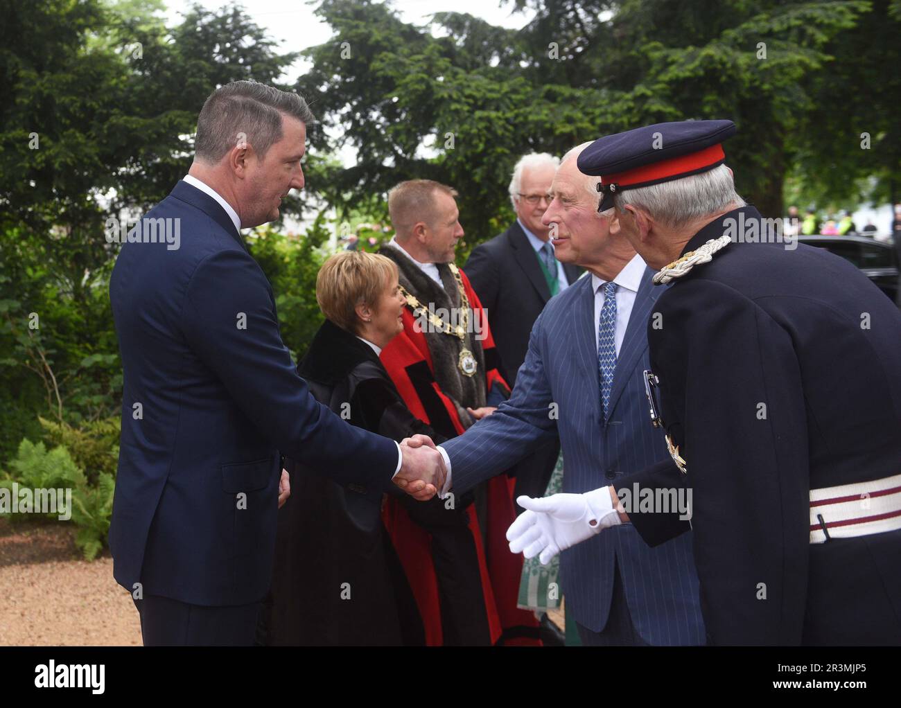 Sinn Fein Politiker John Finucane (links) trifft König Karl III. Und Königin Camilla (versteckt) während ihres Besuchs, um einen neuen Krönungsgarten in Newtownabbey zu eröffnen und mit den Designern des Gartens und Vertretern von Gemeinwesen und Wohltätigkeitsorganisationen zusammenzutreffen, Erfahren Sie, wie der Garten den Beginn einer neuen grünen Initiative für den Gemeinderat von Antrim und Newtownabbey markiert, während eines zweitägigen Besuchs in Nordirland. Bilddatum: Mittwoch, 24. Mai 2023. Stockfoto