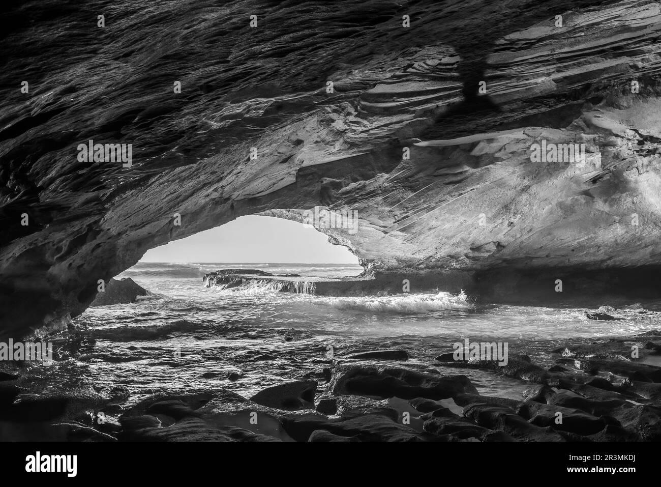 Im Inneren der Waenhuiskrans Cave bei Arniston in der Provinz Westkap. Der Indische Ozean ist sichtbar. Schwarzweiß Stockfoto