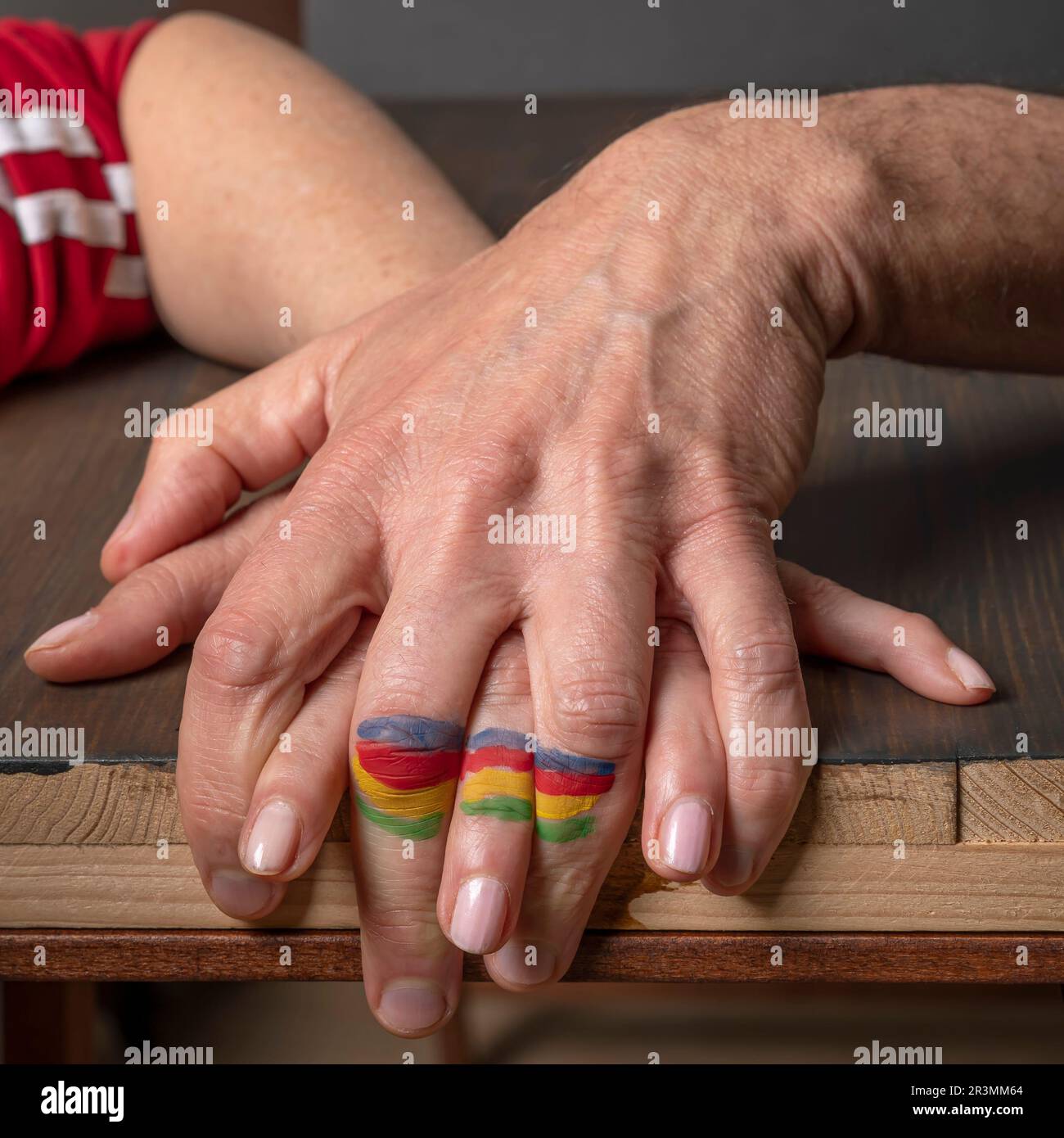 Eine weibliche Hand ist mit einer männlichen Hand verbunden und bildet eine farbige Fahne an den Fingern Stockfoto