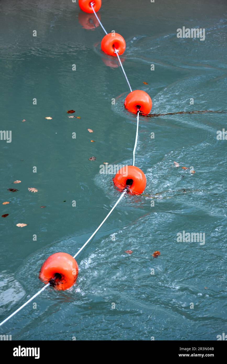 Schwimmende rote Kunststoffbojen erzeugen in fließendem Wasser Riffeln Stockfoto