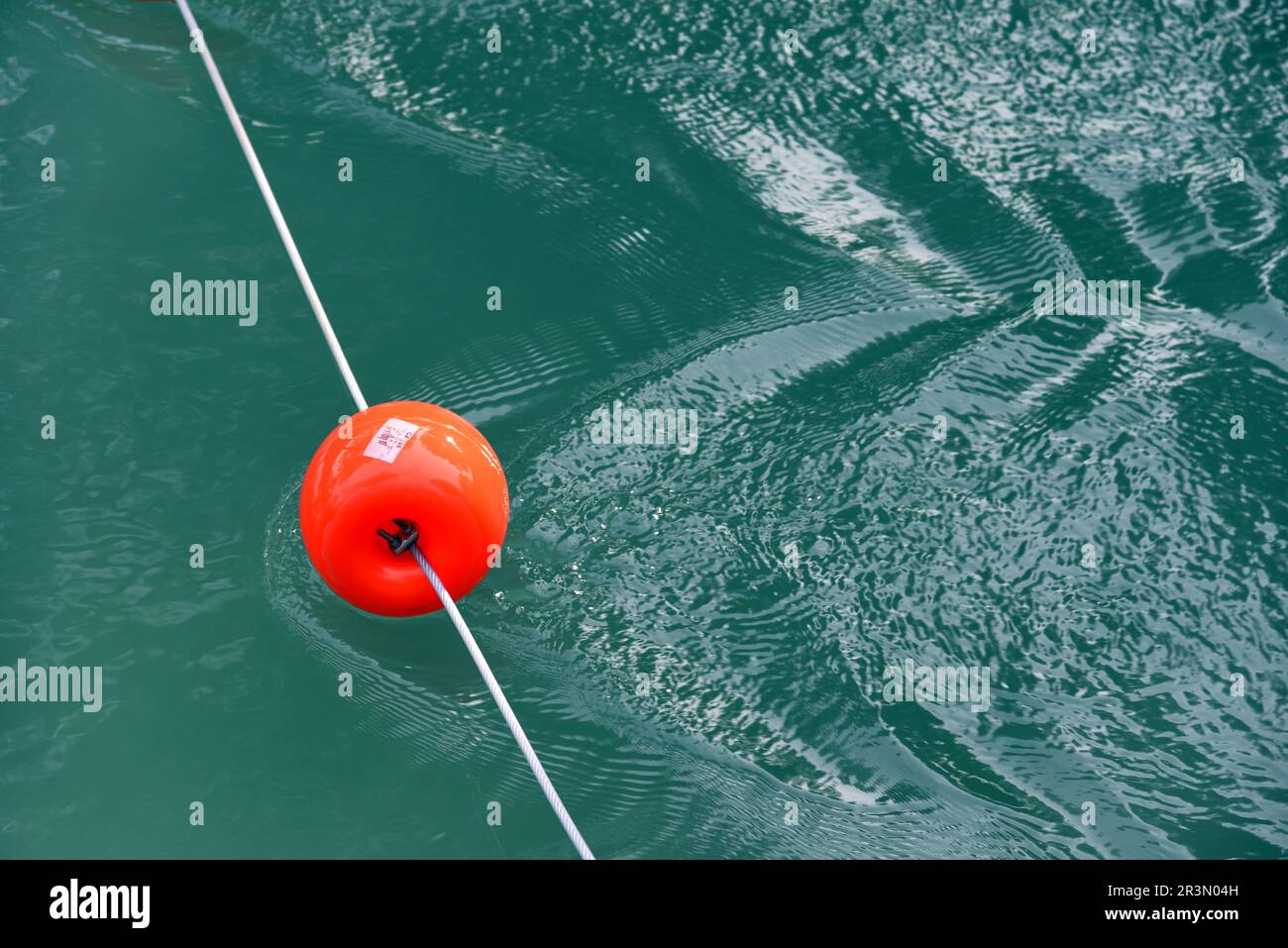 Schwimmende rote Kunststoffbojen erzeugen in fließendem Wasser Riffeln Stockfoto