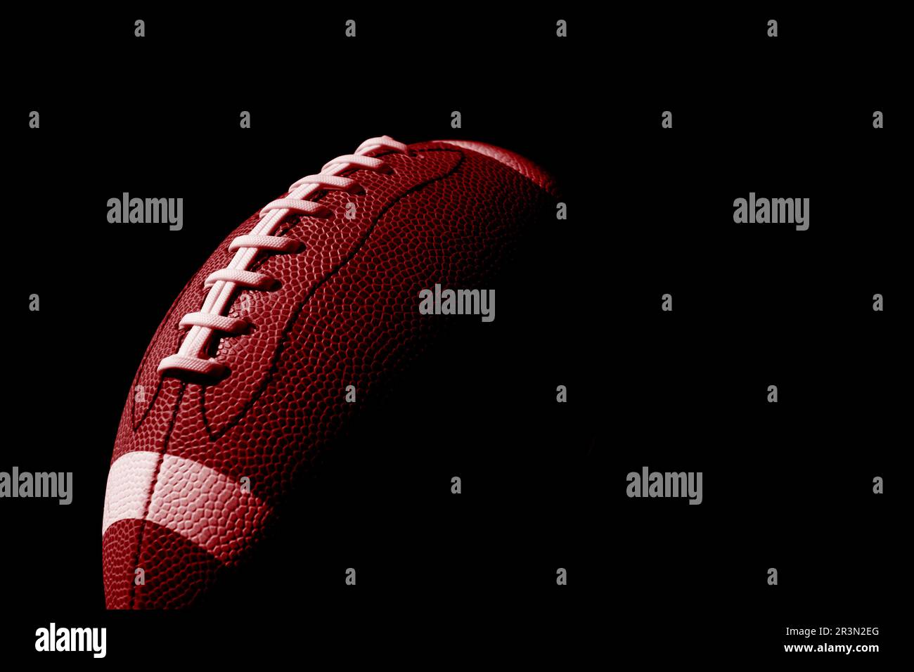 Roter American Football-Ball Nahaufnahme auf schwarzem Hintergrund. Horizontales Sportposter, Grußkarten, Kopfzeilen, Website und App Stockfoto