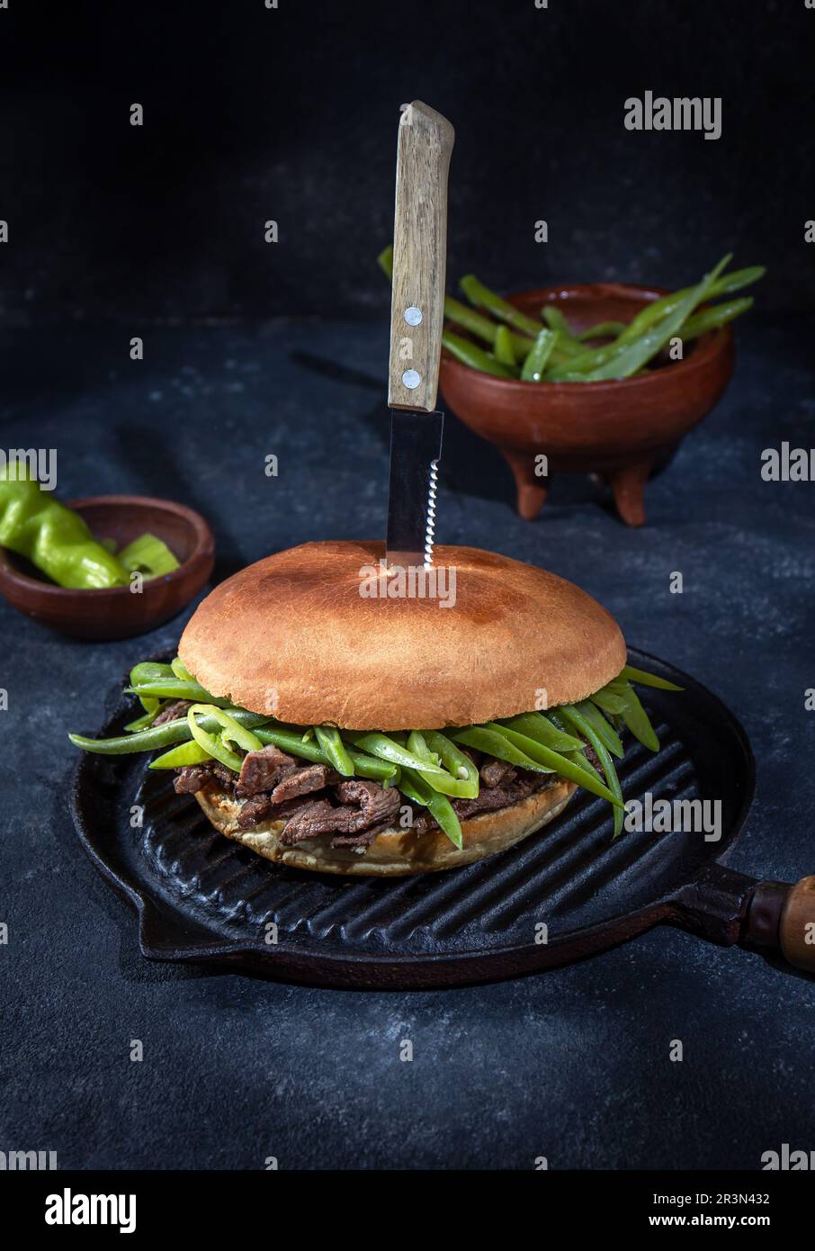 Chilenischer lateinamerikanischer Sandwich-Burger Chacarero mit hochwertigen Rinderschnitten und grünen Bohnen auf schwarzem Hintergrund. Stockfoto