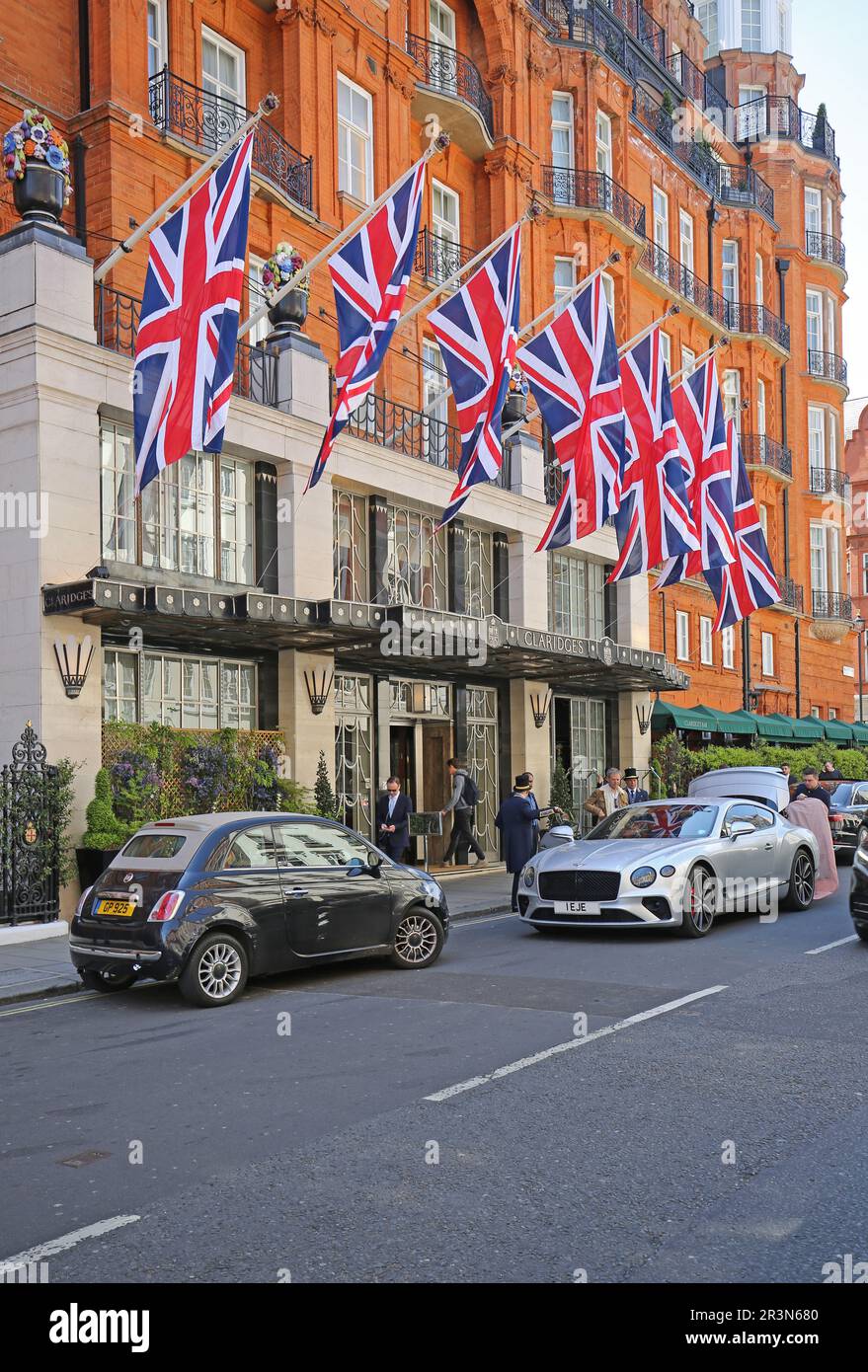 Haupteingang zum Claridges Hotel, Mayfair, London, Großbritannien. Ein Gast wird seinem Bentley von Hotelpersonal unterstützt. Stockfoto