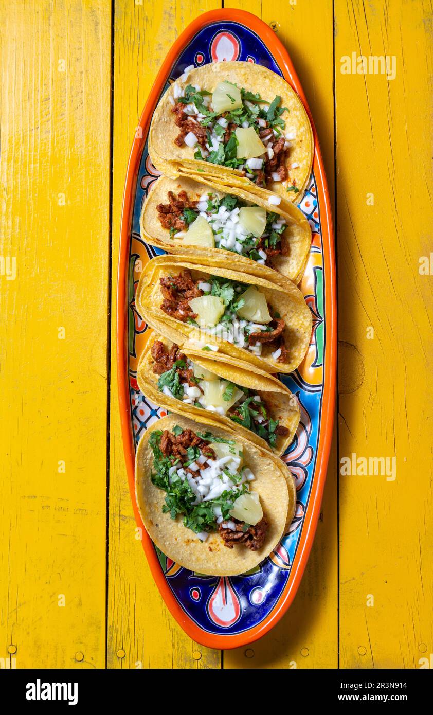 Mexikanischer Hintergrund mit Tacos al Pastor und mexikanischen Saucen. Gelber Holzhintergrund, Kopierbereich, Draufsicht Stockfoto