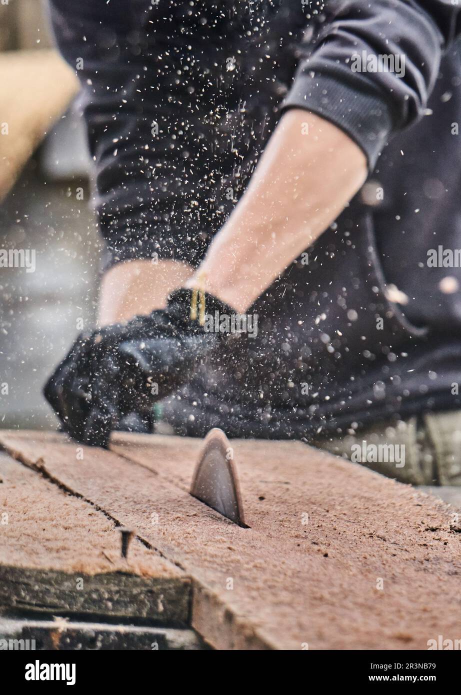 Hochwinkel des Ernteguts anonymer Zimmermann in Freizeitkleidung und Handschuhen Sägeblätter aus Holz mit alternder Sägemaschine bei der Arbeit in der Gemeinschaft OT Stockfoto