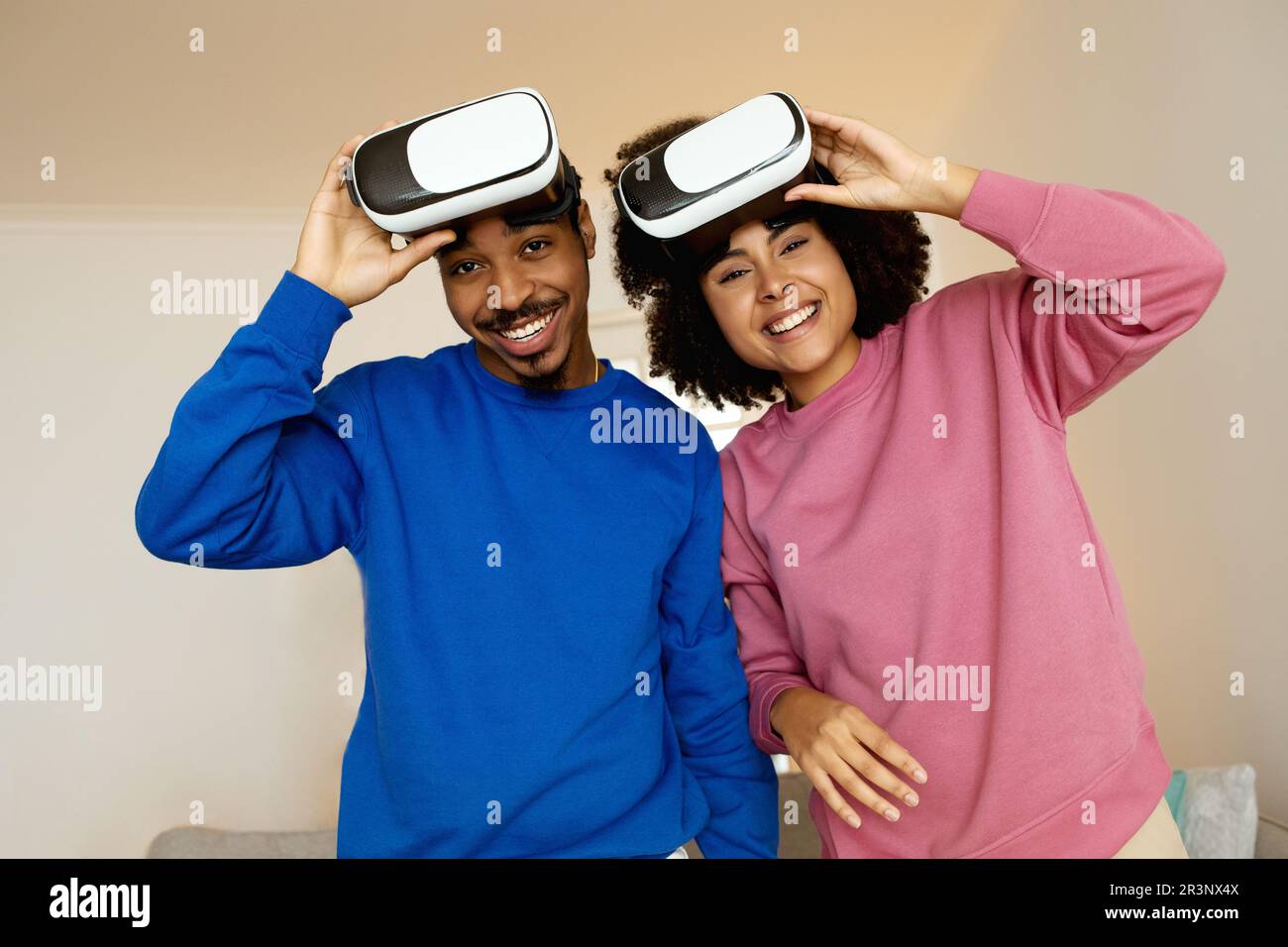 Glückliche schwarze Ehepartner, die zu Hause mit VR-Brillen posieren Stockfoto