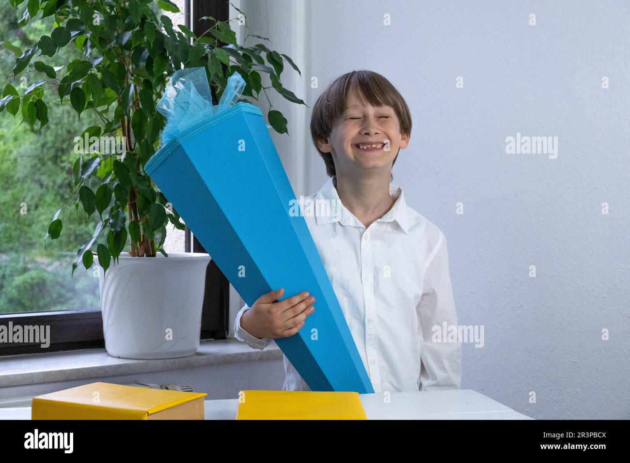 Glückliches Kind, das am ersten Schultag traditionelle deutsche Süßigkeiten in der Hand hielt. Stockfoto