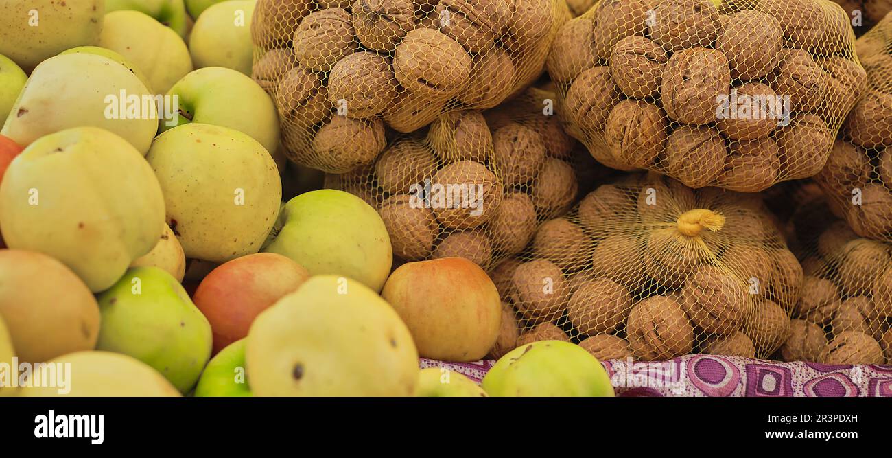 Walnüsse und Äpfel auf der Theke auf dem Bauernmarkt, selektiver Fokus auf reife Produkte, Vorführung in Lebensmitteln Stockfoto