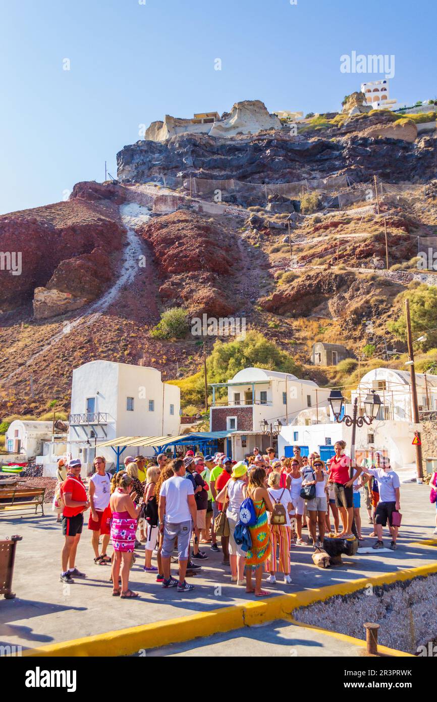 Touristen am Hafen von Oia. Tausende kommen jedes Jahr an, um einen Urlaub in den malerischen Dörfern von Caldera zu verbringen. Bewundern Sie die Aussicht und die Dörfer hoch oben Stockfoto