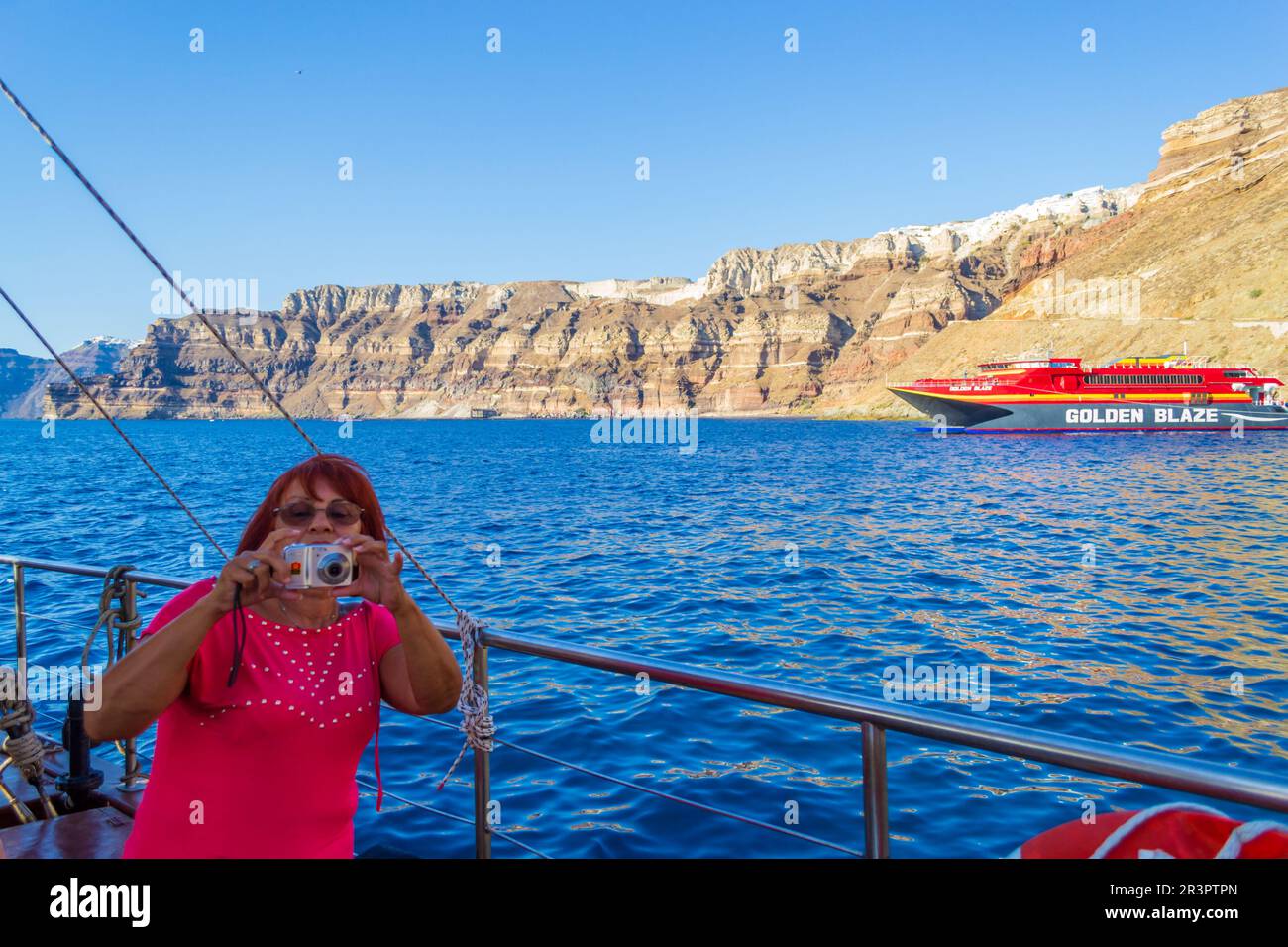 Touristen, die mit dem Boot in der Nähe der Mauer von Santorin fahren. Tausende kommen jedes Jahr, um einen Urlaub in den malerischen Dörfern von Caldera, Griechenland, zu verbringen Stockfoto