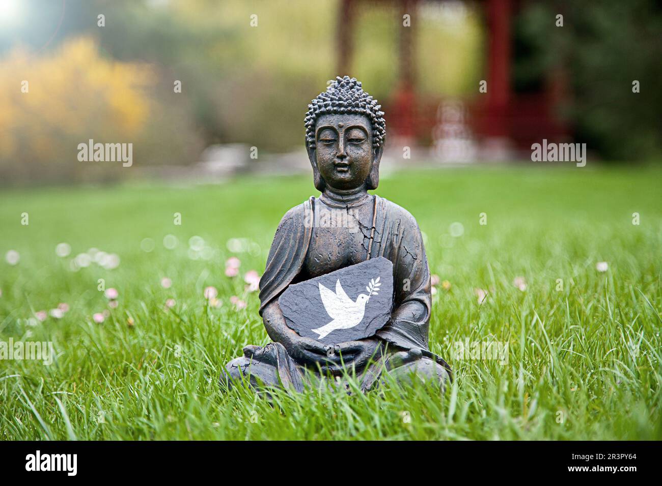 Buddha-Statue auf einer Wiese mit einer Friedentaube Stockfoto