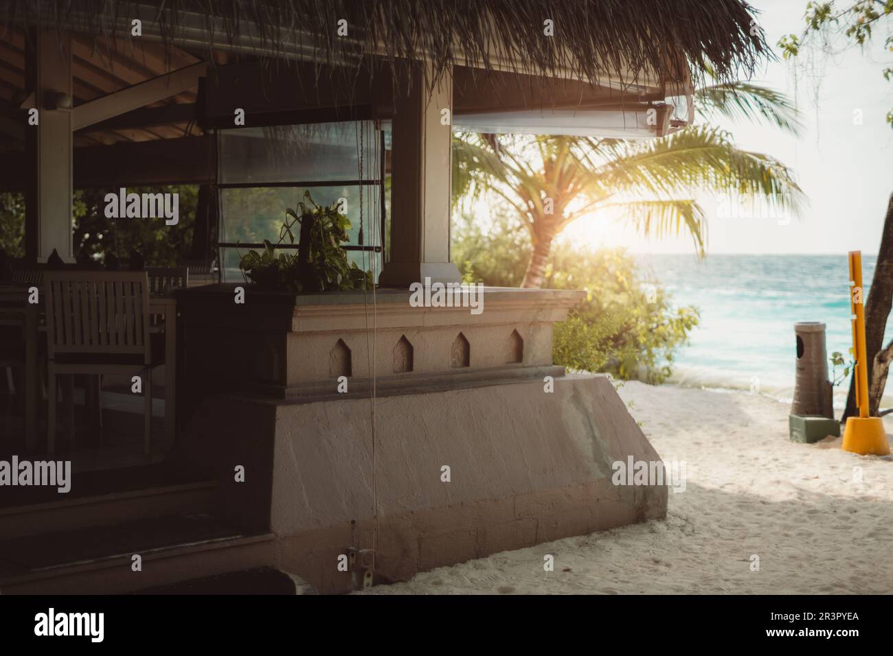 Sonniger Tag in einem Sandstrand Café aus Sandstein mit Strohdach. Palmen, die es umgeben, sind hinten zu sehen, vor dem Meer, Provid Stockfoto