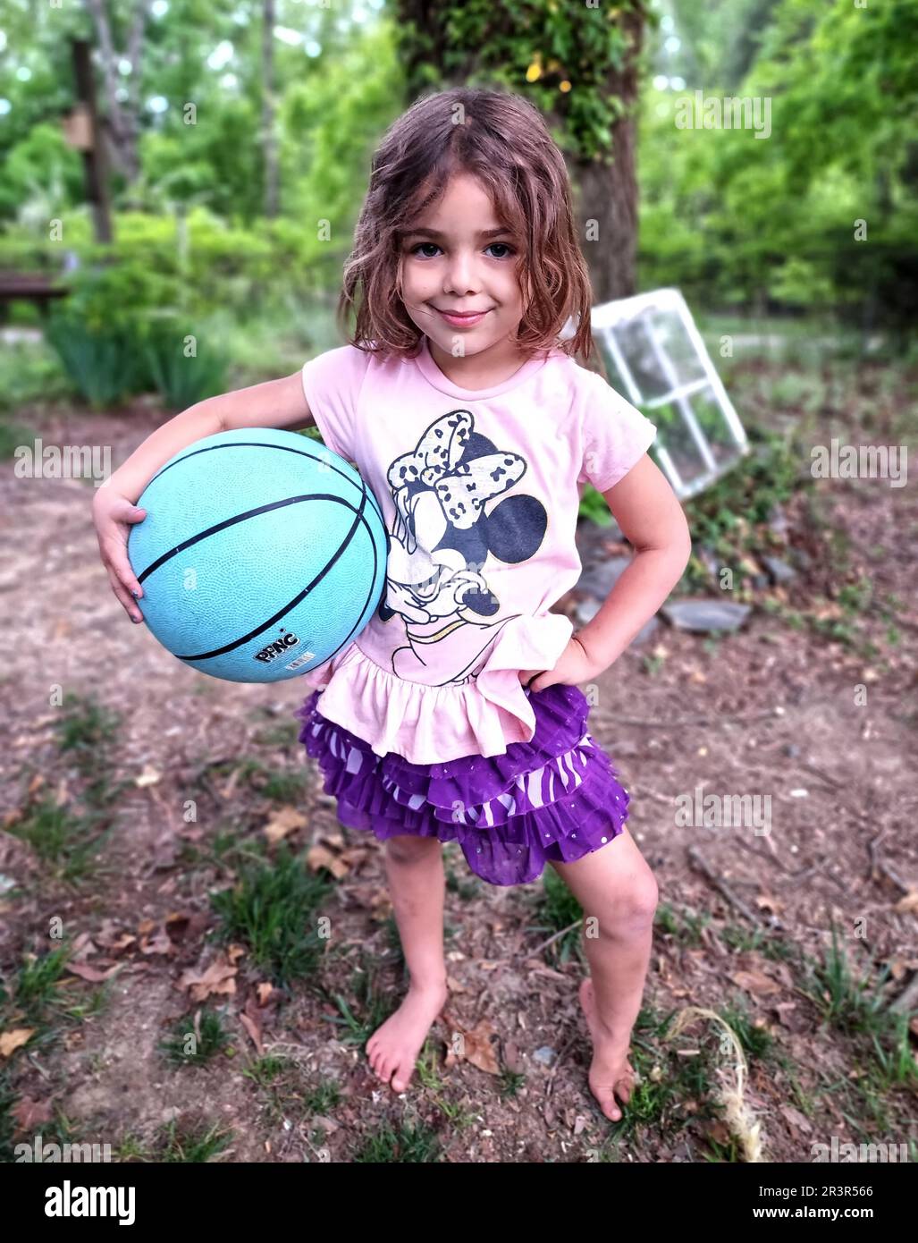 Kleines Mädchen, das draußen mit einem Basketball für die Kamera posiert (NC State, 2023) Stockfoto