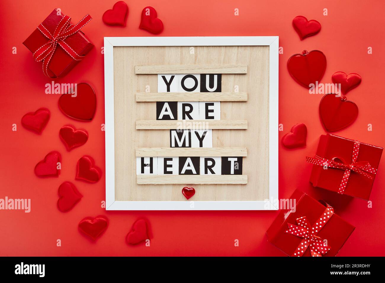 Brieftafel mit Herzen und Geschenkboxen auf rotem Hintergrund. Draufsicht. Hintergrund für Valentinstag Stockfoto