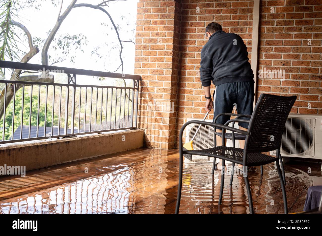 Ein Mann putzte nach starkem Regen den Balkon Stockfoto