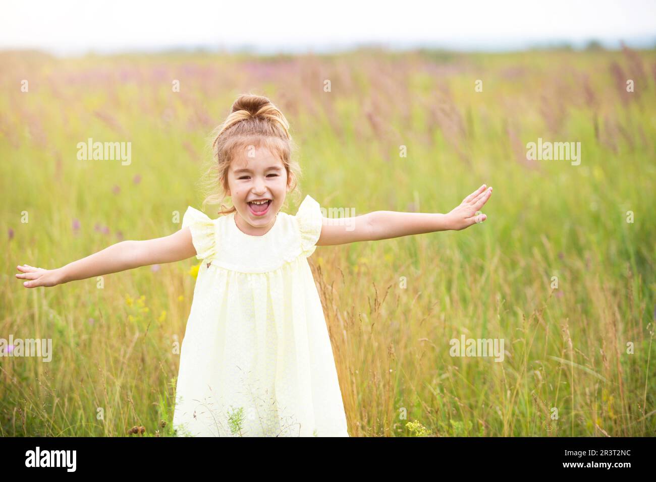Das Mädchen rennt ins Feld mit ausgestreckten Armen wie ein Flugzeug. Sorgenfreie Kindheit, Sommerfreiheit, Reisen. Internatio Stockfoto