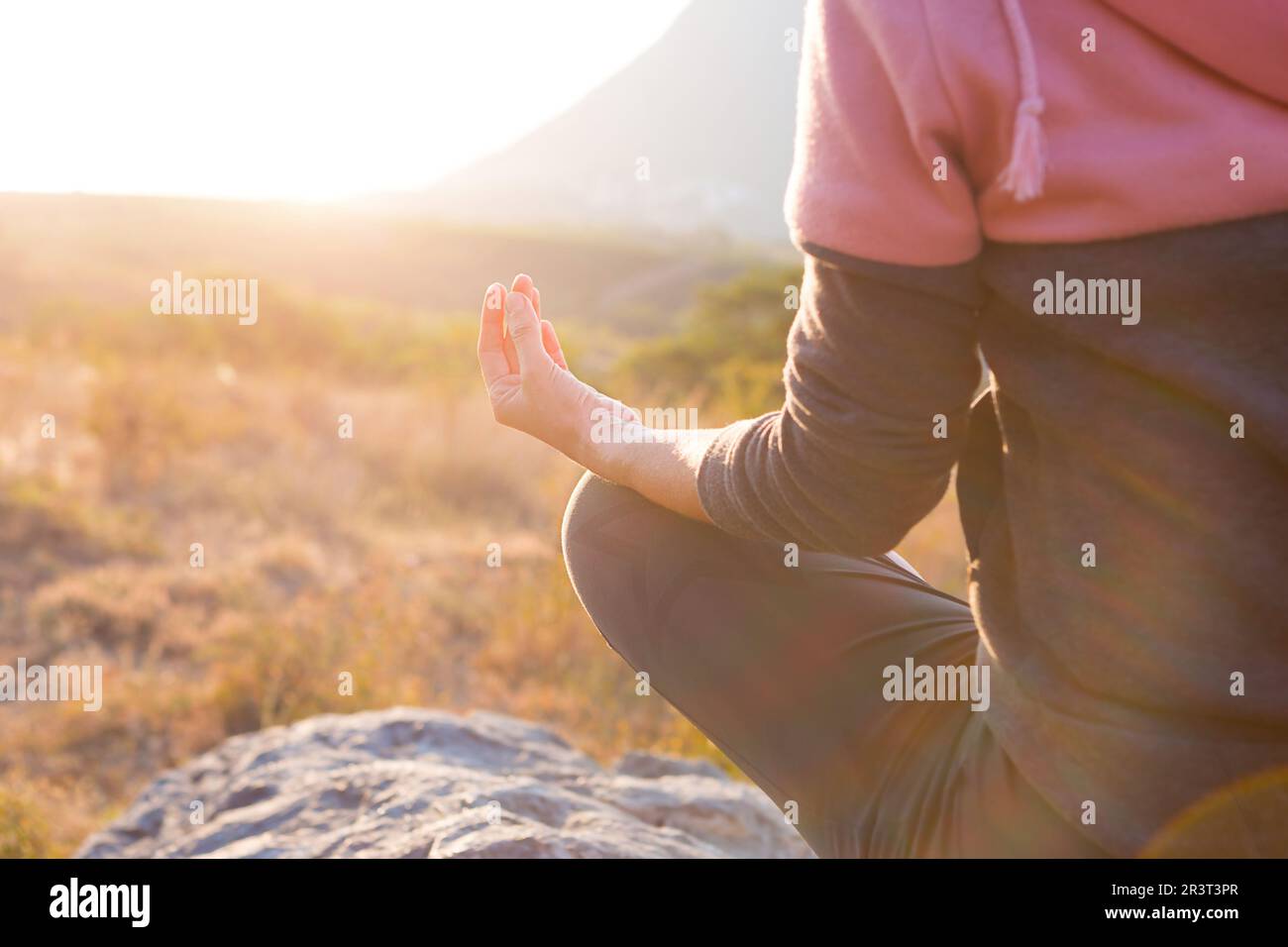 Eine Frau sitzt auf einem Felsen in Lotusposition mit geschlossenen Fingern, als Zeichen von Harmonie, Entspannung und Meditation. Yoga, ich selbst. Stockfoto