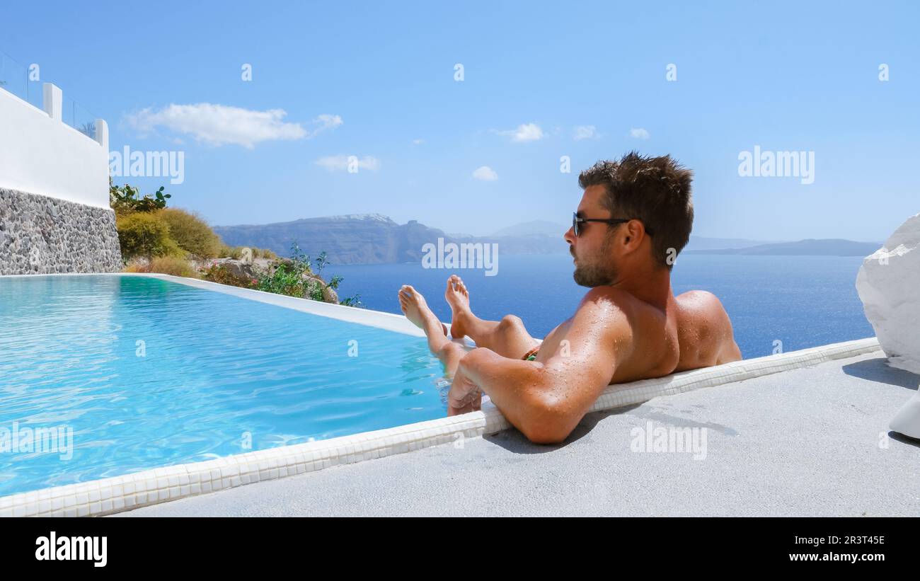 Junger Mann, der sich während des Urlaubs im Santorini Infinity im Swimmingpool mit Blick auf den Ozean erholte Stockfoto
