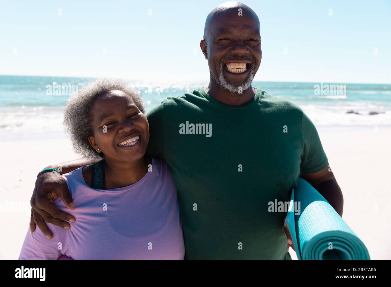 Fröhliches afroamerikanisches Seniorenpaar, das seinen Urlaub am Strand am Meer und am klaren Himmel verbringt Stockfoto