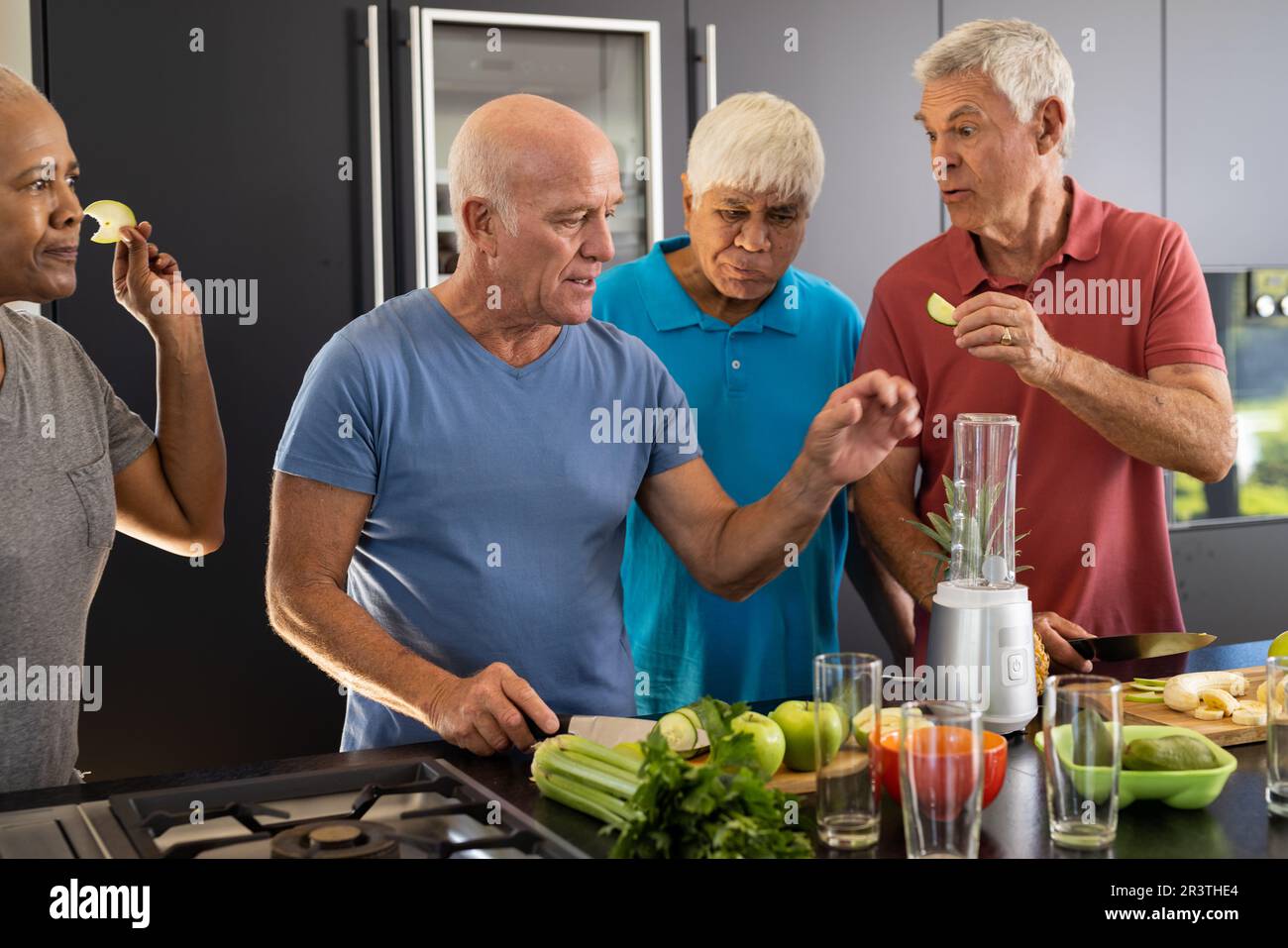 Glückliche, vielfältige Senior-Freunde diskutieren Zutaten für die Zubereitung gesunder Smoothies in der Küche Stockfoto